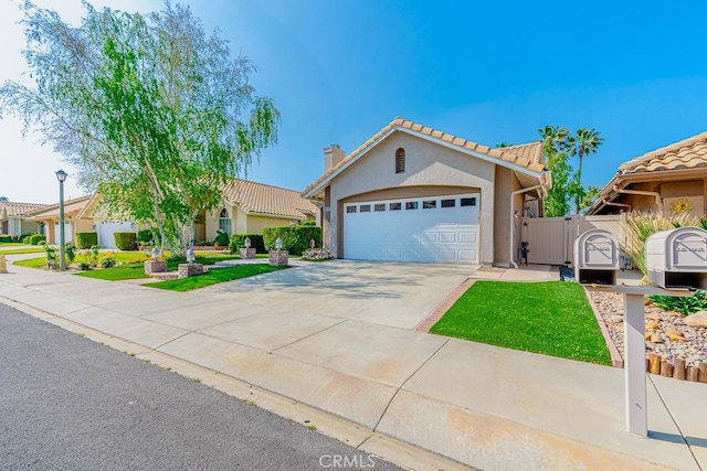 view of front of property with driveway, a gate, a tiled roof, stucco siding, and a garage