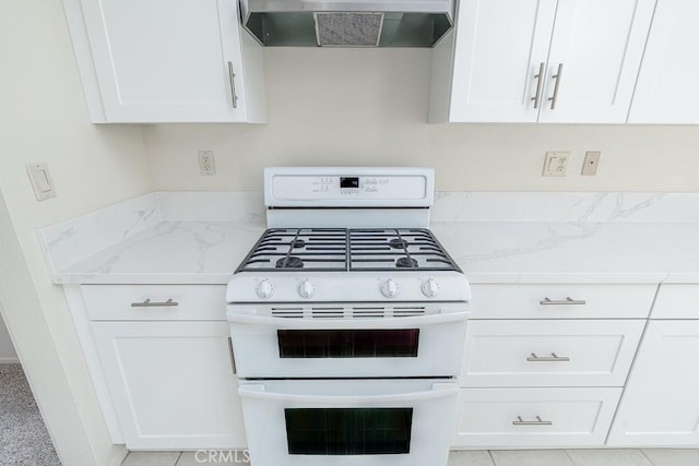 kitchen with range with two ovens, white cabinetry, wall chimney range hood, and light stone countertops
