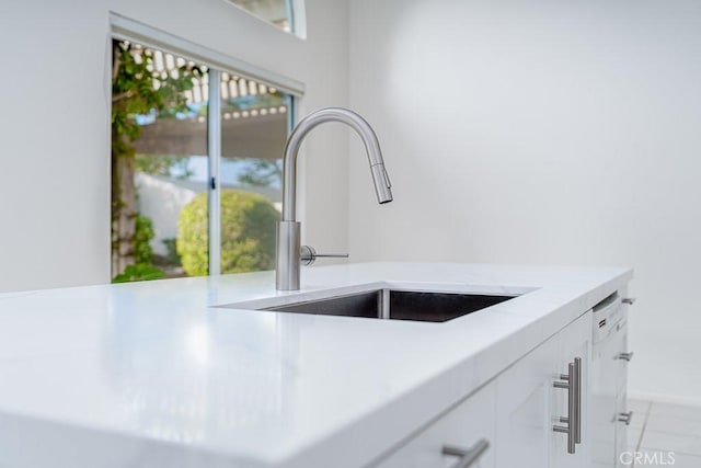 room details with light countertops, white cabinets, and a sink