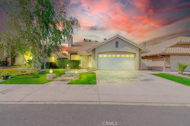 view of front of property featuring a tile roof, a yard, stucco siding, concrete driveway, and an attached garage