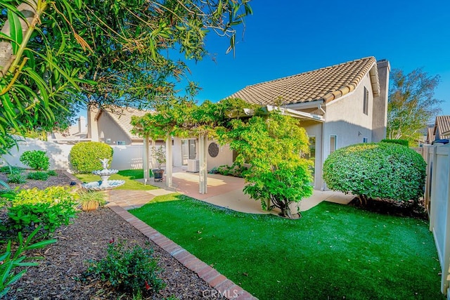rear view of house with a lawn, a fenced backyard, stucco siding, and a patio area