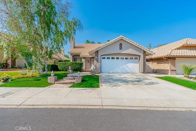 view of front of house featuring driveway, a tiled roof, an attached garage, stucco siding, and a front lawn