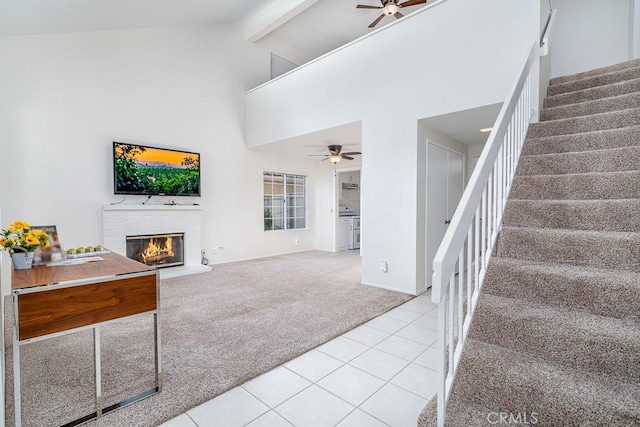 unfurnished living room with stairs, light colored carpet, ceiling fan, a fireplace, and high vaulted ceiling
