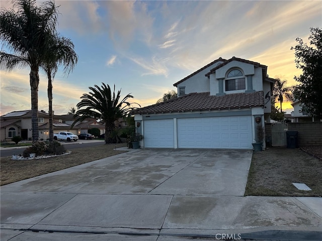 view of front of home with stucco siding, a tiled roof, concrete driveway, and fence