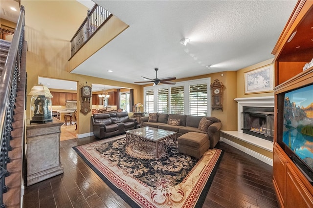 33931 Baystone St, Temecula, CA 92592 - living room featuring a glass covered fireplace, baseboards, ceiling fan, dark wood-style flooring, and a textured ceiling