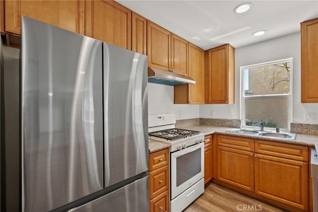 26145 Gravett Pl, Saugus, CA 91350 - kitchen featuring freestanding refrigerator, under cabinet range hood, white gas range, light wood finished floors, and a sink