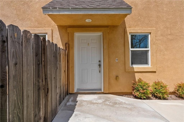 26145 Gravett Pl, Saugus, CA 91350 - doorway to property featuring stucco siding, fence, and roof with shingles