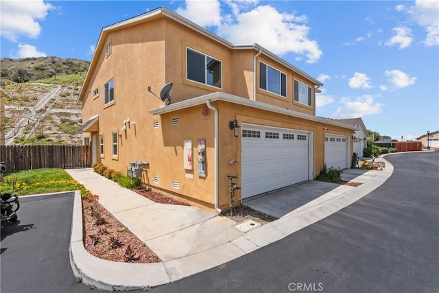 26145 Gravett Pl, Saugus, CA 91350 - view of side of property with fence, aphalt driveway, stucco siding, and a garage