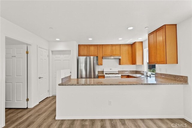 26145 Gravett Pl, Saugus, CA 91350 - kitchen featuring light wood finished floors, brown cabinets, freestanding refrigerator, and white gas range oven