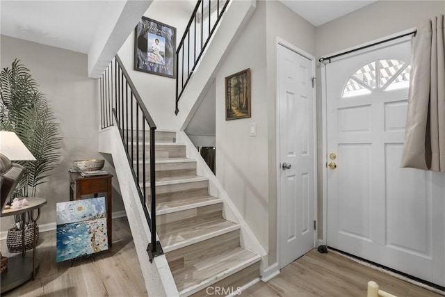 entrance foyer with stairway, wood finished floors, and baseboards