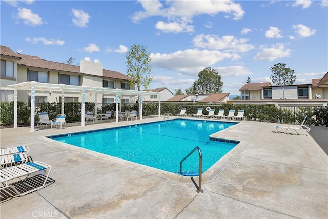 community pool featuring fence, a pergola, a patio, and a residential view