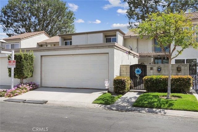 view of front of house with stucco siding, a tiled roof, a gate, driveway, and an attached garage