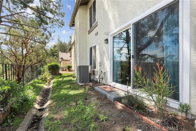 view of property exterior featuring fence, central AC unit, and stucco siding