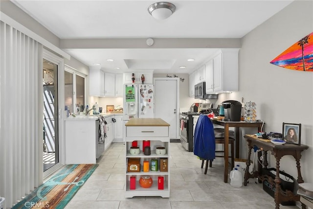 kitchen with open shelves, appliances with stainless steel finishes, a kitchen island, white cabinets, and light tile patterned flooring