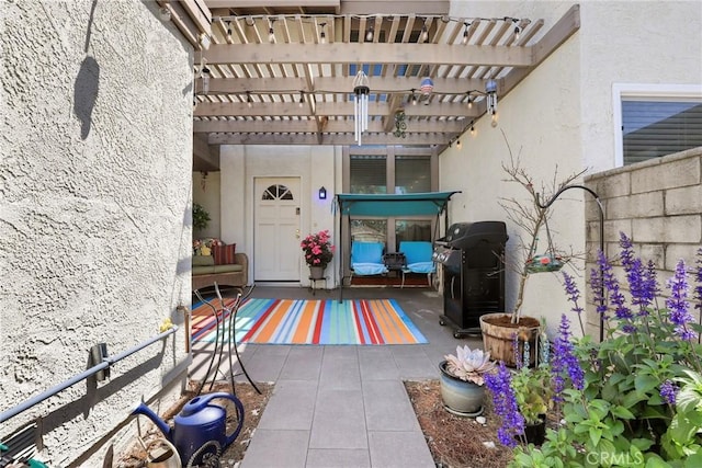 view of exterior entry featuring a patio, a pergola, and stucco siding