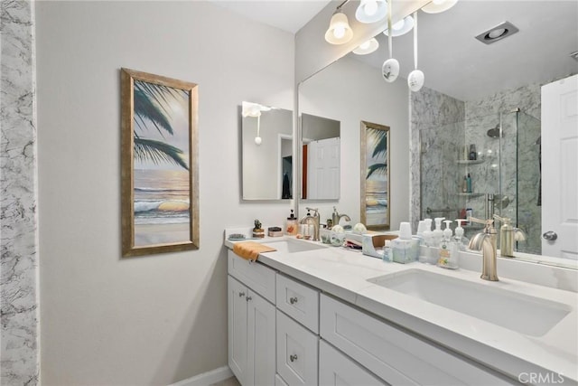 bathroom featuring baseboards, a shower stall, double vanity, and a sink