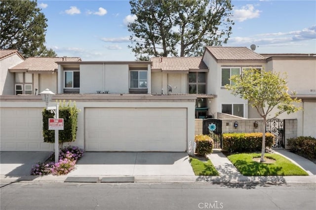 multi unit property with stucco siding, a tiled roof, concrete driveway, and an attached garage