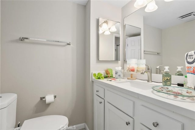 half bath with visible vents, toilet, and vanity