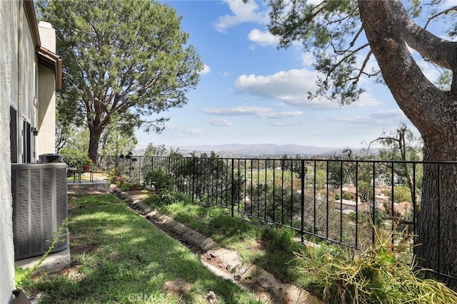 view of yard featuring a mountain view, fence, and central AC unit