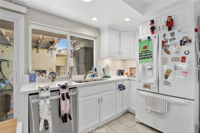 kitchen featuring white cabinetry, light countertops, white refrigerator with ice dispenser, and a sink