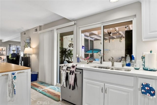 kitchen featuring white cabinets, a sink, visible vents, light tile patterned flooring, and dishwasher