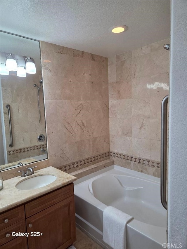 412 Arenoso Ln Unit 102, San Clemente, CA 92672 - full bathroom with a textured ceiling, vanity, a garden tub, a shower, and tile walls