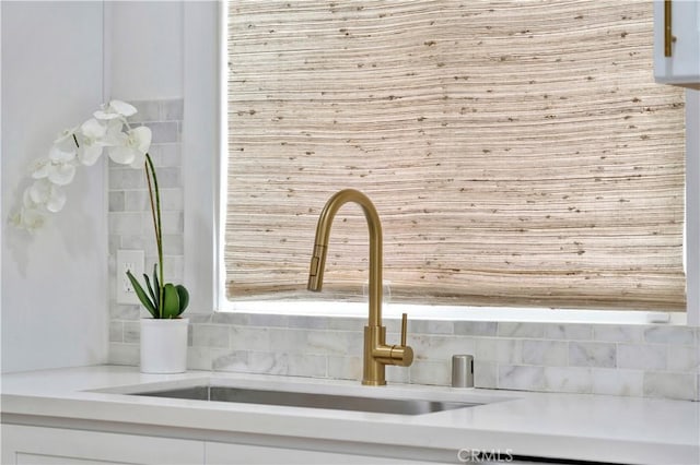 room details with a sink, light countertops, and white cabinetry