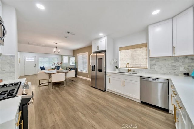 kitchen featuring a sink, a notable chandelier, white cabinets, and stainless steel appliances