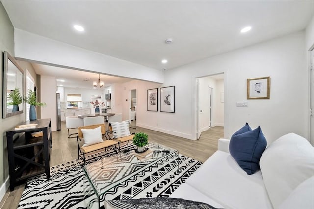 living room with light wood-style floors, recessed lighting, baseboards, and a notable chandelier