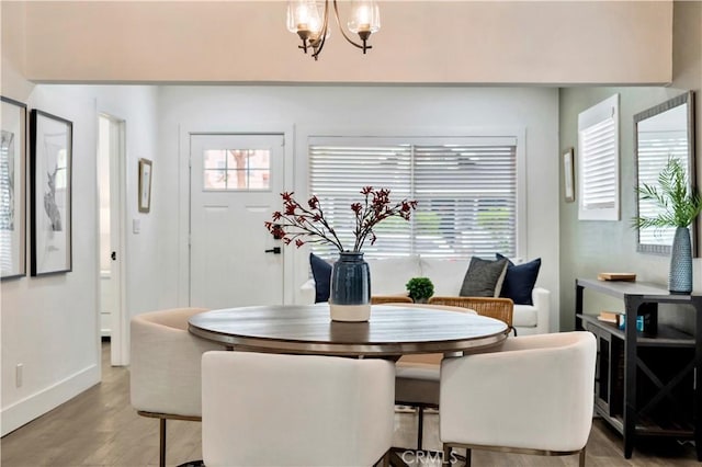 dining room featuring baseboards, a notable chandelier, and light wood finished floors
