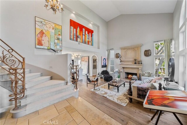 2009 Via Aguila, San Clemente, CA 92673 - living room with a chandelier, high vaulted ceiling, stairs, a warm lit fireplace, and wood finished floors