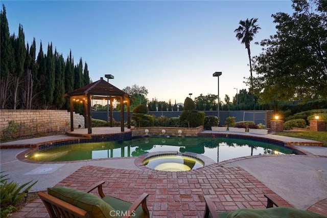 10313 Christine Pl, Chatsworth, CA 91311 - pool at dusk featuring a gazebo, a fenced backyard, and a pool with connected hot tub