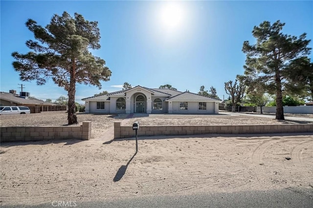 view of front of property featuring stucco siding, fence, and a tile roof