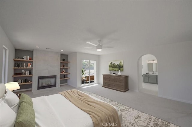 bedroom with a large fireplace, baseboards, arched walkways, carpet floors, and ensuite bathroom