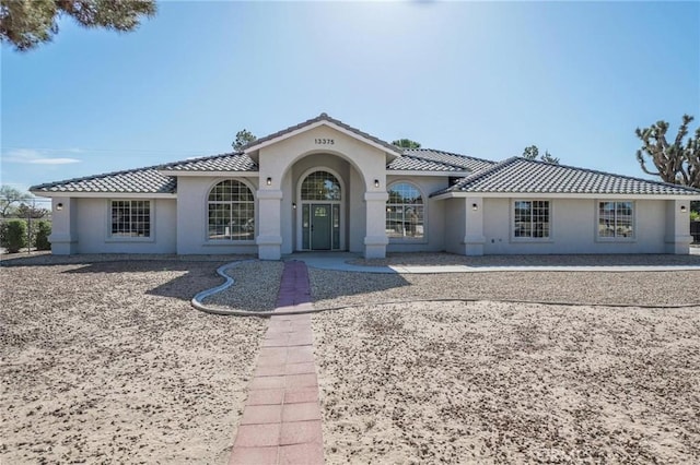 mediterranean / spanish house with stucco siding and a tiled roof