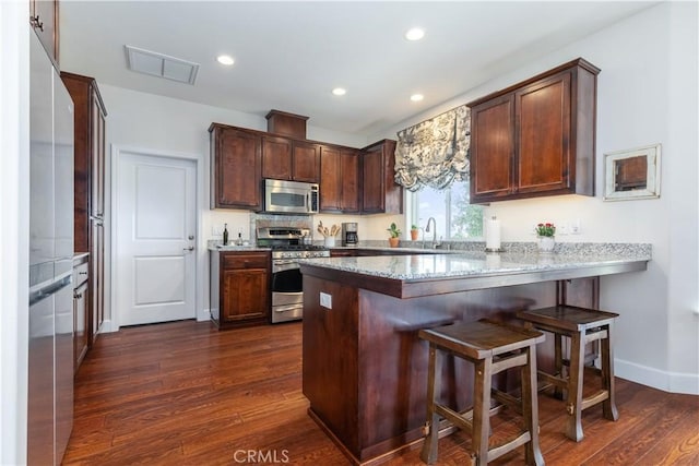 1835 Rancho Lomas Way, San Miguel, CA 93451 - kitchen with appliances with stainless steel finishes, a peninsula, dark wood-style floors, a kitchen breakfast bar, and baseboards