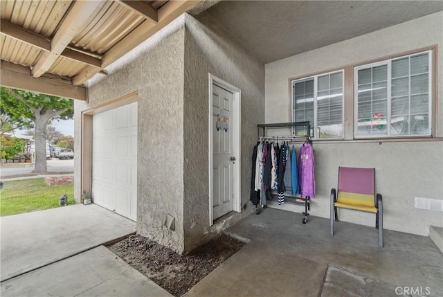 view of exterior entry with an attached garage and stucco siding