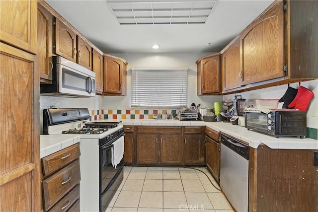 kitchen featuring brown cabinetry, visible vents, a toaster, stainless steel appliances, and light tile patterned flooring