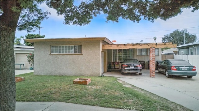 ranch-style house with stucco siding, driveway, a front yard, and fence