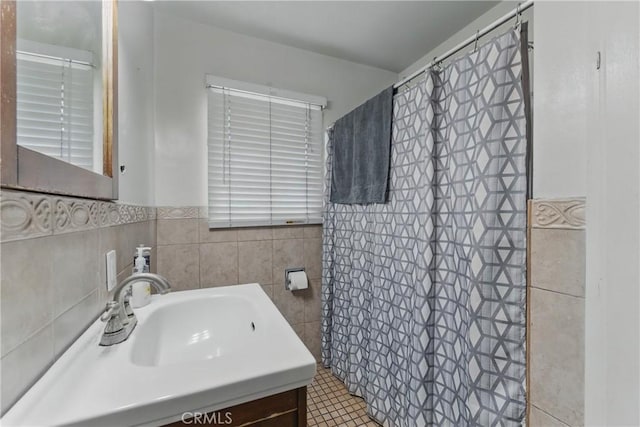 full bath featuring vanity, wainscoting, a shower with shower curtain, and tile walls