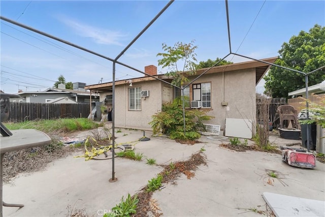 back of house with fence, a chimney, a patio area, and stucco siding