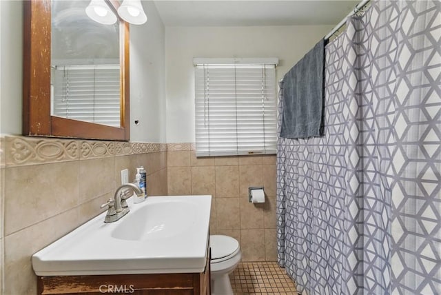 full bath featuring vanity, toilet, a shower with shower curtain, a wainscoted wall, and tile walls