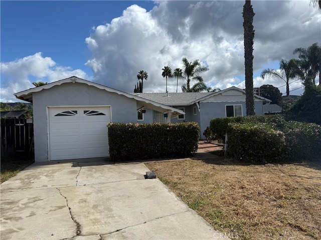 ranch-style home featuring fence, stucco siding, concrete driveway, and an attached garage