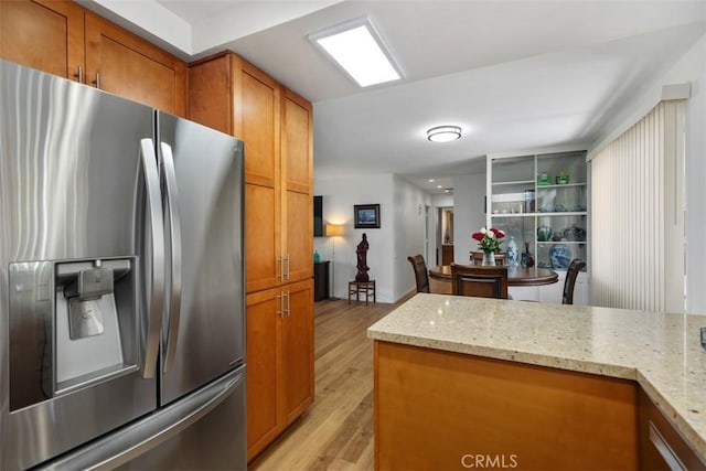 5472 Paseo Del Lago E Unit B, Laguna Woods, CA 92637 - kitchen with stainless steel fridge, brown cabinetry, light wood-style floors, and light stone counters