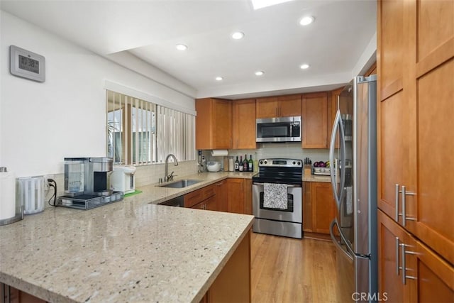 5472 Paseo Del Lago E Unit B, Laguna Woods, CA 92637 - kitchen with appliances with stainless steel finishes, a sink, brown cabinetry, light stone counters, and recessed lighting