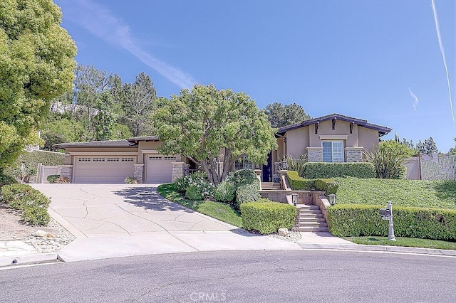 view of front of house with an attached garage, concrete driveway, stone siding, and stucco siding