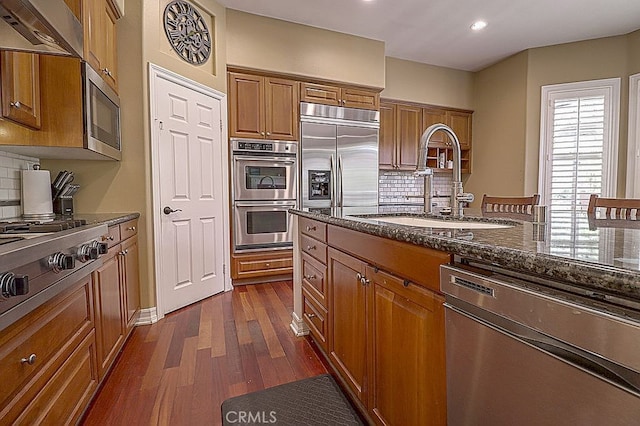 kitchen with built in appliances, range hood, and brown cabinets