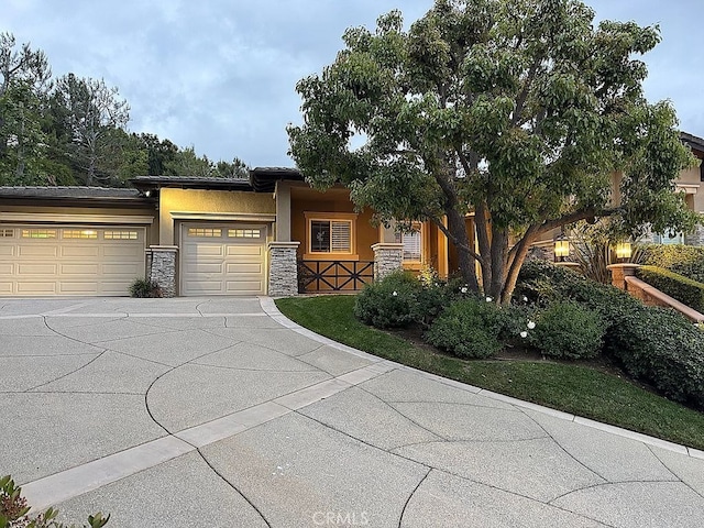 view of front of home featuring driveway, stone siding, an attached garage, and stucco siding