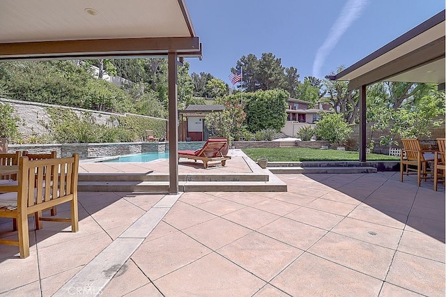 view of patio with an outbuilding, a shed, an outdoor pool, and a fenced backyard