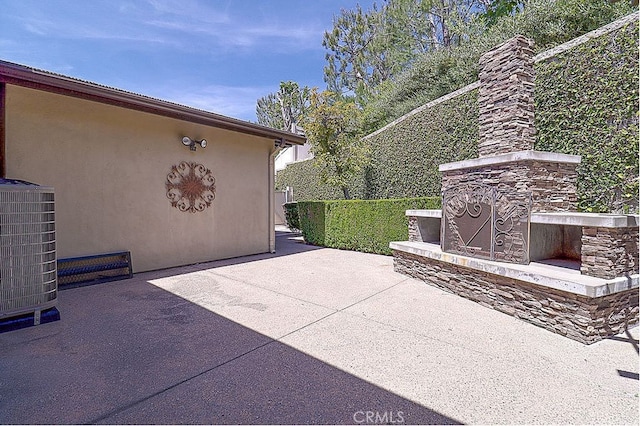 view of patio / terrace featuring cooling unit and an outdoor stone fireplace